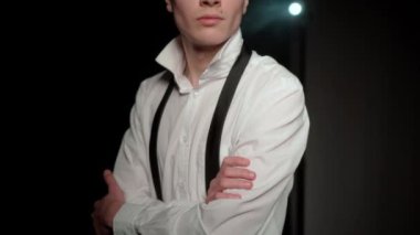 Karanlık bir odadaki dalgın genç adam. Kollarını kavuşturan beyaz gömlekli ciddi bir adamın portresi. İçsel sakinlik ve özgüven.