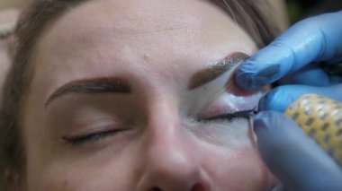 Kirpik çizgisi pigmenti makyajı. Dövme uzmanının yakın plan çalışması..