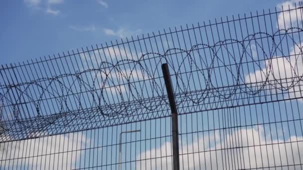 在蓝天和云彩的映衬下 有铁丝网的栅栏 封闭区 难民营中的资金 — 图库视频影像