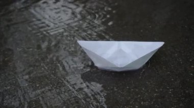 Yağmur suyunun yüzeyinde kağıt tekne. Karaya oturalım. Her işte başarısızlığın sembolü. Basit bir çocuk oyuncağı..