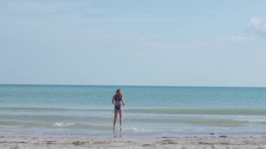 Genç bir kız güneşli bir yaz gününde dalgaların üzerinden atlar. Sakin mavi denizde ya da okyanusta yüzmek. Deniz kenarında kaygısız bir tatil..