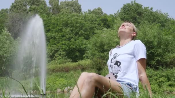 Женщина Средних Лет Отдыхает Парке Сидя Траве Наслаждаясь Теплыми Лучами — стоковое видео