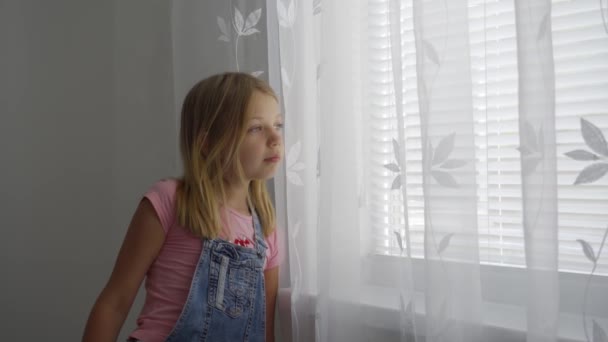 Young School Age Girl Home Looks Out Window White Curtain — Stock Video