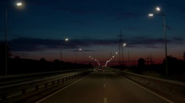 Karanlıkta ekspres yol. Güneşe doğru ilerliyoruz. Şehirler arasında az trafiği olan bir yol. Parlak ışıklar yolu aydınlatır. Arabayla seyahat kavramı.