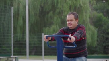 Şehir parkındaki bir bisiklette özenle spor yapan bir adamın yüz ifadesi. Sağlıklı bir hayat sürmeye çalışan sıradan insanlar..