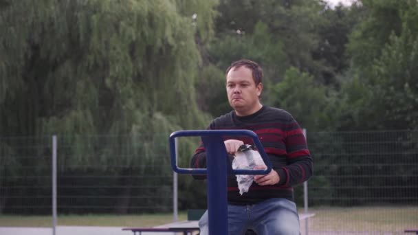 Obese Man Eet Chips Tijdens Het Sporten Een Sportsimulator Voedselverslaving — Stockvideo