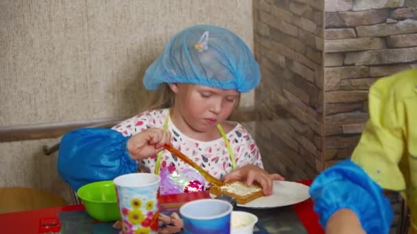 Mutfağında Küçük Bir Kız Özenle Bir Sandviçe Tereyağı Sürüyor — Stok video