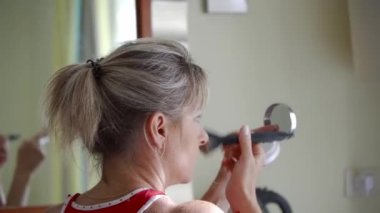 Orta yaşlı bir kadın sabah evde günlük makyaj yapar. Yüzündeki lekeleri makyajla gizle.