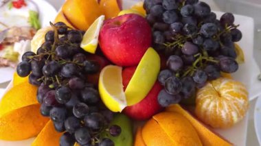 Bir tepside çeşitli meyveler: üzüm, elma, portakal, limon, armut, meyve karışımı