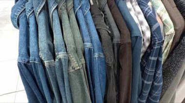 Elbise mağazasında askılarda asılı tişörtler.