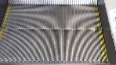 Sarı güvenlik çizgileri olan yürüyen bir yürüyen merdivenin metal basamakları.