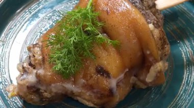 Çıtır çıtır derili, kahverengi domuz budu deriden bir filiz ile servis edilir..