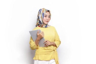 Tabletteki kadınlar tesettür elbisesi kullanıyor. Güzel tesettürlü kadın elinde tabletle kameraya bakıyor..