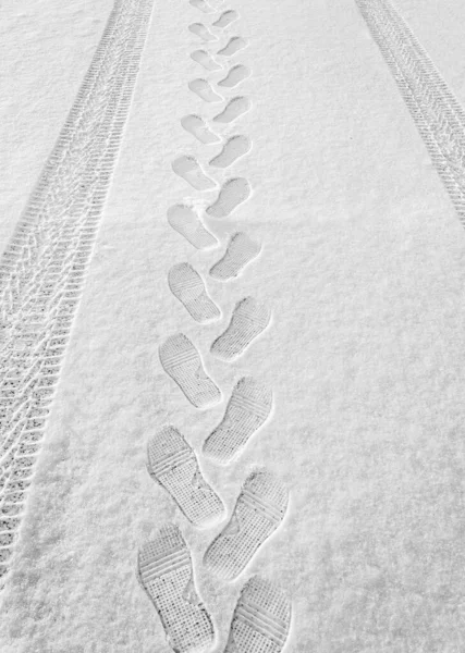 冬季在薄薄的白雪上有节奏的脚印 车辙和车胎进入远方 垂直的框架 有肋的脚印 冬季的概念特写 — 图库照片