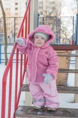 Kız korkuluk ve gülümsüyor tutunarak slaytları, merdivenlerden geliyor. Kış.