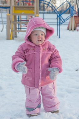 Kız. Gülümseyen, aşağı ve uzakta bakarak. Yanağında bir yırtık. Kış.