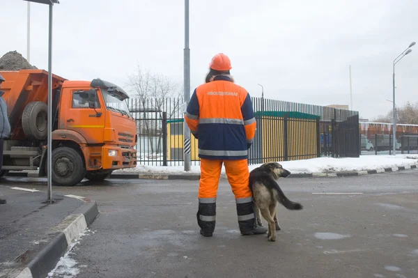 Karyawan Mosvodokanal dengan anjing mengawasi pintu masuk truk dengan salju di titik salju mencair Moskow — Stok Foto