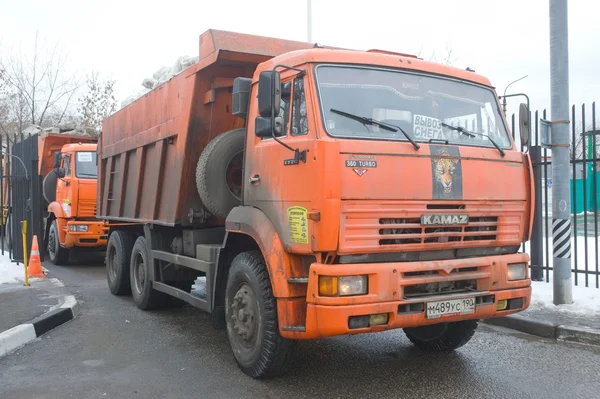 Camión volquete naranja KAMAZ entra en un punto de fusión de nieve en Moscú —  Fotos de Stock