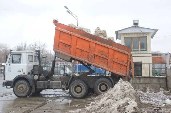 Unloading dirty snow from the back of the orange car in negotable on snow-melting point, Moscow — Stock Photo, Image