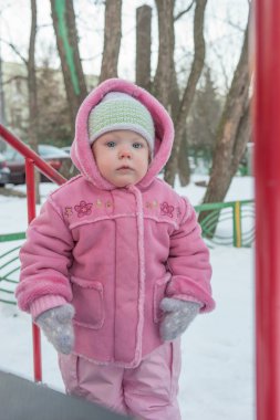 Tek ve yün eldiven bakar, yakınındaki tepenin ayakta bir yarım yıl-yaşlı kız. Kış.