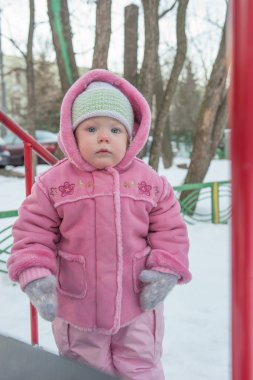 Tek ve bir yarım kız pembe bir koyun derisi içinde bakar, hill yakınındaki ayakta. Kış.