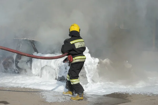 En brandman släcker en bil på undervisningarna av departement av nödsituationer, Moskva Royaltyfria Stockbilder