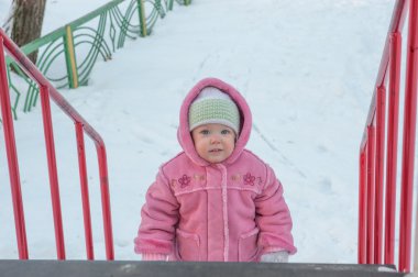 Bir ve yarım bir kız duruyor merdiven slaytlar ve gülümsüyor alt kısmında