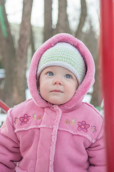 One and a half year old girl skeptical smiles and looks up. Winter. — Stock Photo, Image