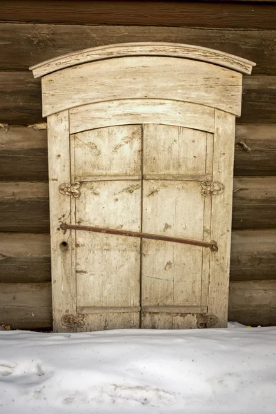 Volets en bois sur une vieille maison sibérienne russe à Irkoutsk, en hiver. La maison est si vieille que les fenêtres entrent dans le sol . — Photo