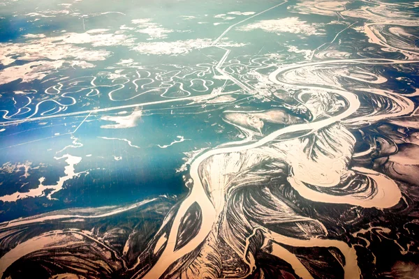 Вид с воздуха на реку на заснеженной лесной равнине — стоковое фото