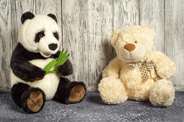 Ursinho de pelúcia e panda brinquedos sentados em uma sala de crianças em fundo de madeira — Fotografia de Stock