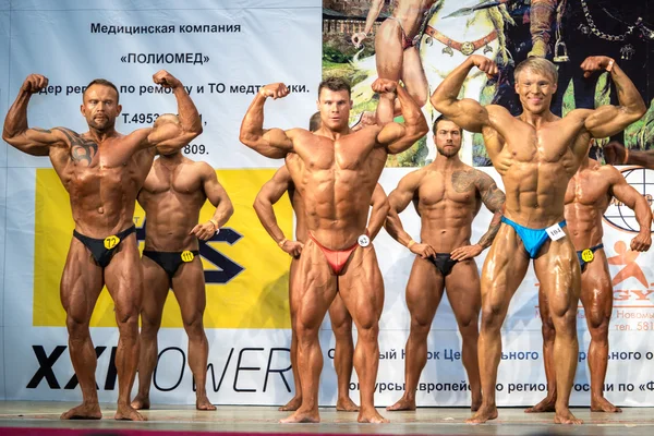 Reutov, Rusya Federasyonu - 02 Nisan 2016: erkekler vücut geliştiriciler tam büyüme gösterir pazı ve karın kasları vücut geliştirme, fitness ve bodyfitness Moscow Region Kupası sırasında. — Stok fotoğraf