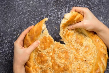 Rustik gri arka plan üzerinde ekmek kırma eller