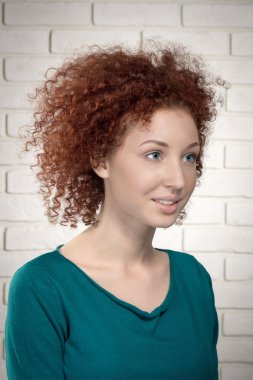 güzel zencefil kıvırcık kadın modeli duvara karşı portresi