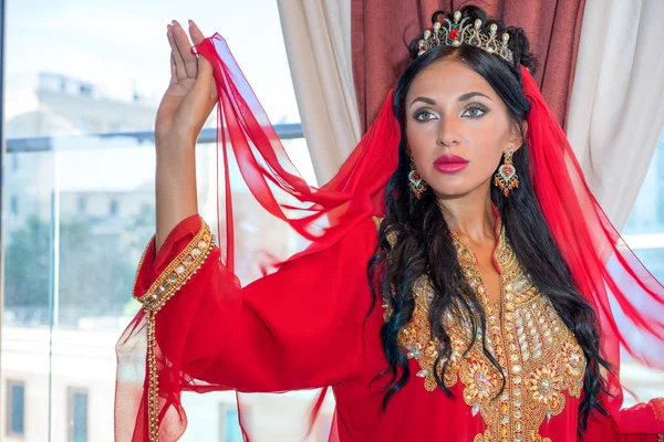 Retrato de una hermosa mujer en vestido oriental. Gracia y belleza. Chica joven en un vestido rojo árabe caro . — Foto de Stock