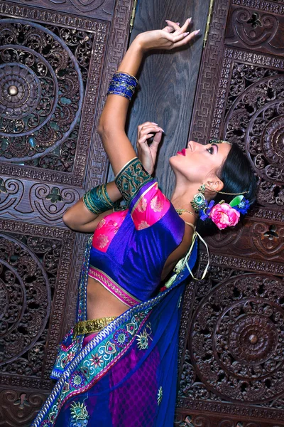 A hagyományos ruhát, fából faragott ajtó mellett a gyönyörű fiatal indiai nő — Stock Fotó