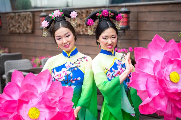 Två asiatiska tjejer på traditionella kinesiska klänningar med paraplyer i form av lotusblommor — Stockfoto