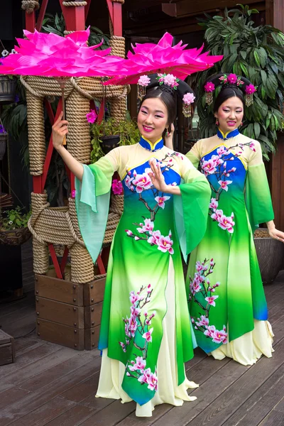 Twee Chinese vrouwen in traditionele Oosterse jurken met ligstoelen in de vorm van lotusbloemen — Stockfoto