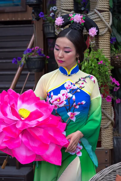 Attraktiva asiatisk kvinna klädd i traditionell kinesisk klänning och blommor parasoll — Stockfoto