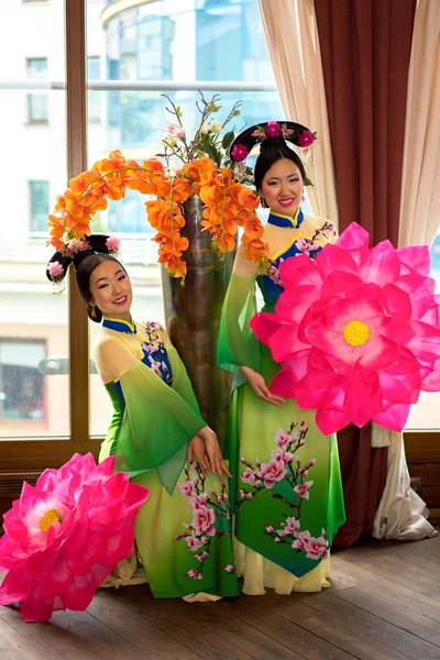 two chinese women in traditional dresses and lotus floral parasol