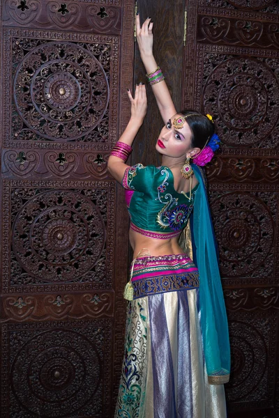 Menina bonita no vestido tradicional indiano nacional de pé de volta no quarto escuro — Fotografia de Stock