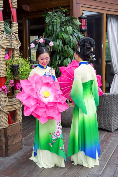 Vackra kinesiska kvinnor i gröna traditionella klänningar och blommig parasoll — Stockfoto