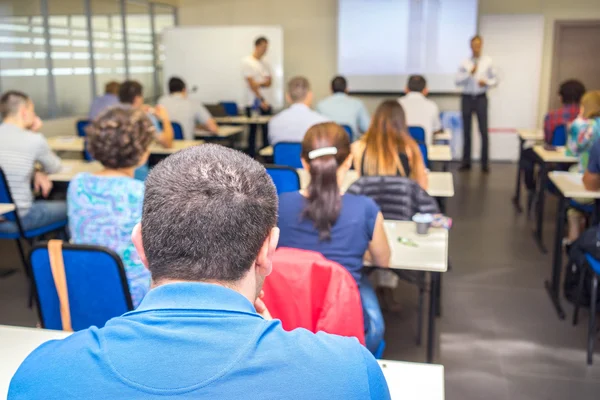 Personer som sitter bak och två lärare nära skrivbordet vid konferensen business — Stockfoto