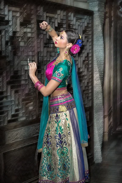 Mulher jovem morena bonita com moda tradicional em pé perto da parede de madeira — Fotografia de Stock