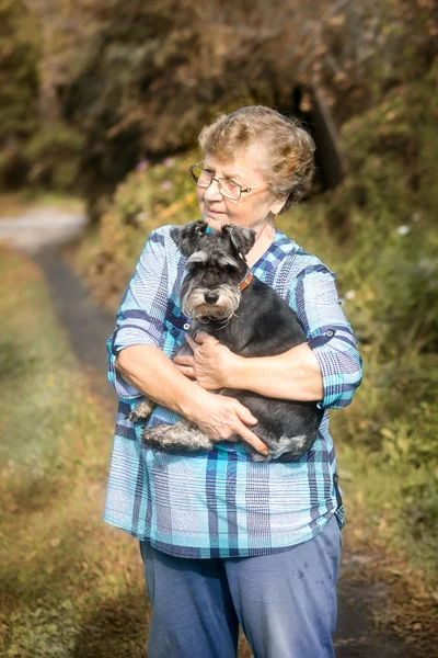 Hermosa mujer sonriente Senior abrazando a su perro en el otoño al aire libre — Foto de Stock