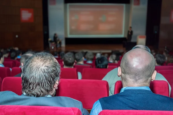 Rückansicht von Geschäftsleuten, die aufmerksam zuhören, während sie auf einer Konferenz sitzen — Stockfoto