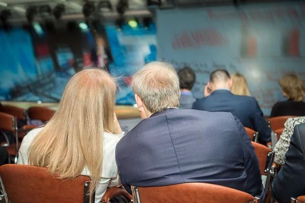 Business conferences concept and ideas. Business audience listening to the presentation in a conference hall. Close up view on the two nearest people. — Stock Photo, Image