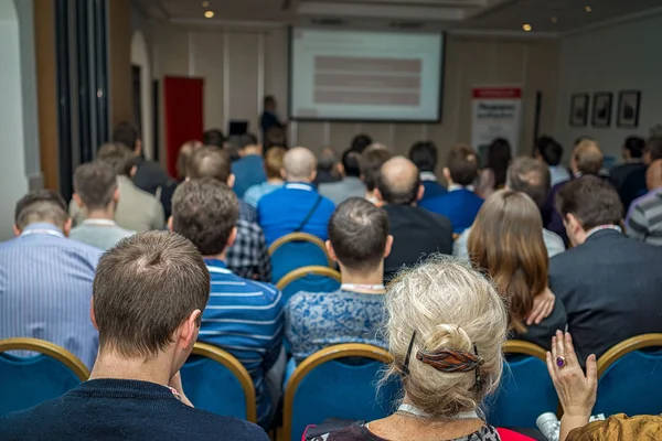 Bakifrån av business folk lyssnar uppmärksamt när du sitter vid konferens — Stockfoto