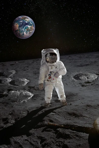 Astronaut on the moon surface with planet Earth behind. Elements of this image furnished by NASA.