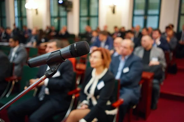 Microphone in focus against blurred audience — Stock Photo, Image